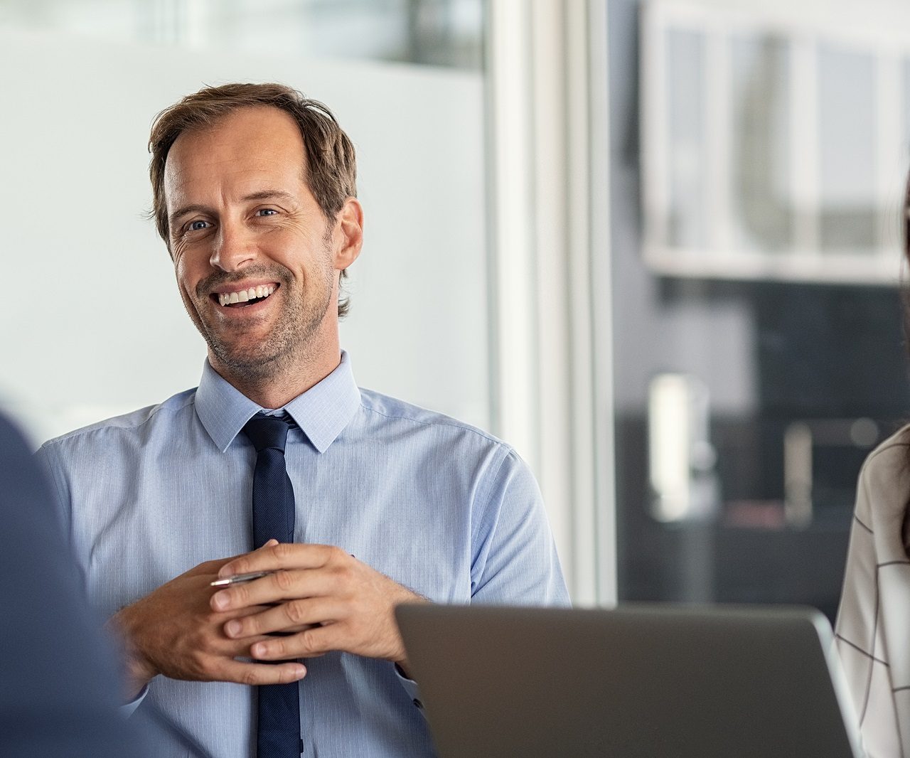 Business partners discussing ideas at meeting. Successful busine Business partners discussing ideas at meeting. Successful businessman listening to colleague during meeting in modern office. Happy mature business man and businesswoman smiling during brainstorming.
